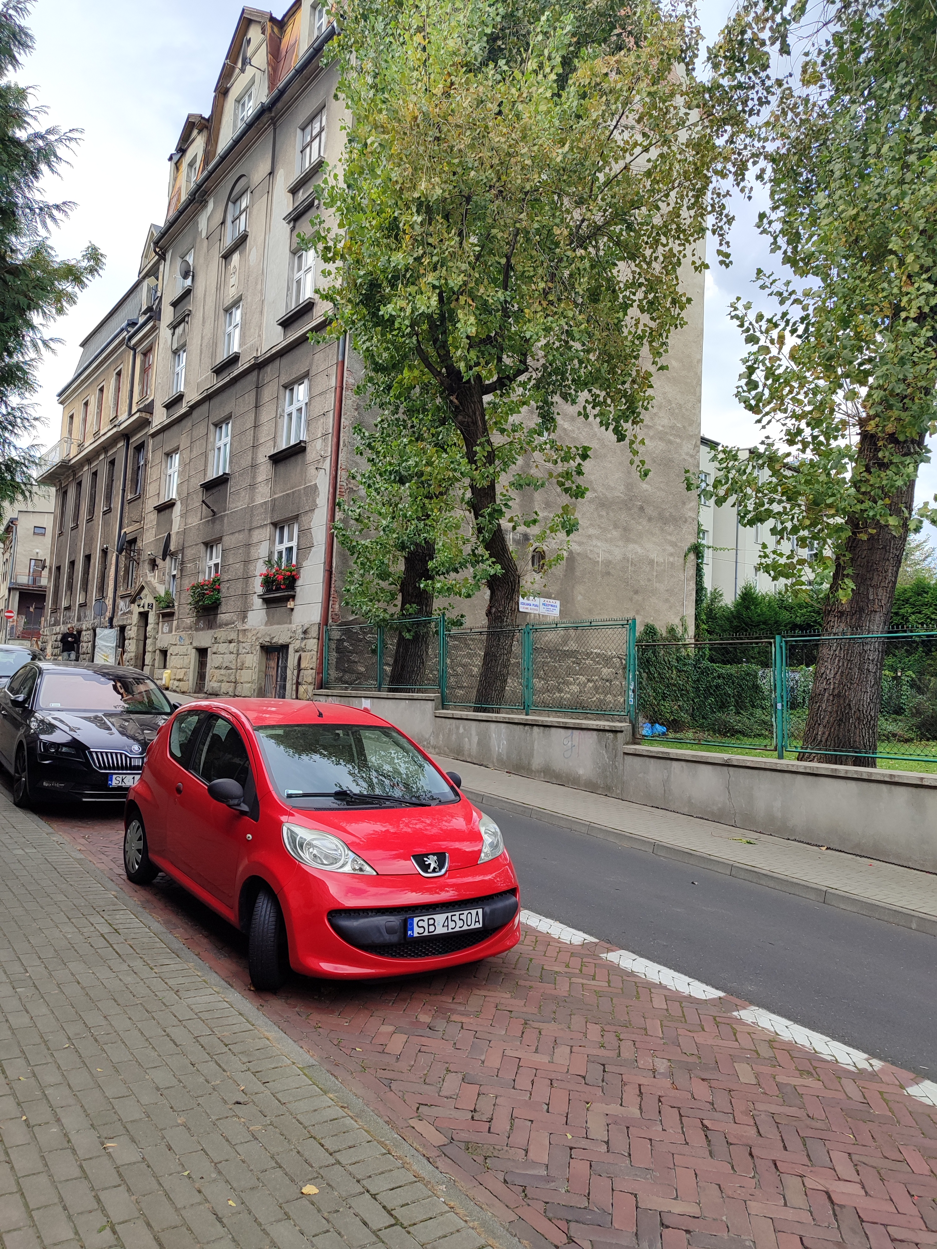 Zdjęcie budynku przy ul. Andrzeja Frycza Modrzewskiego 2 z ulicy z zaparkowanymi przed budynkiem samochodami