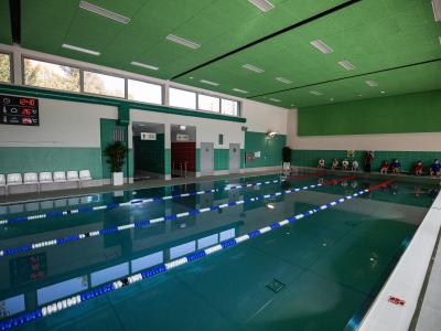 Zdjęcie przedstawiające kryty basen pływacki z torami i zielonym sufitem.