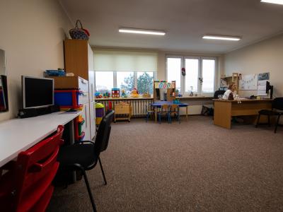 Zdjęcie przedstawiające pokój do zajęć terapeutycznych z biurkami, komputerami i zabawkami dla dzieci.