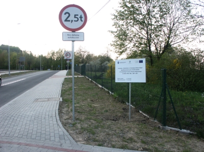 Przebudowa ul. Karbowej w Bielsku-Białej - na zdjęciu fragment drogi, znaki drogowe, tablica informacyjna oraz zieleń