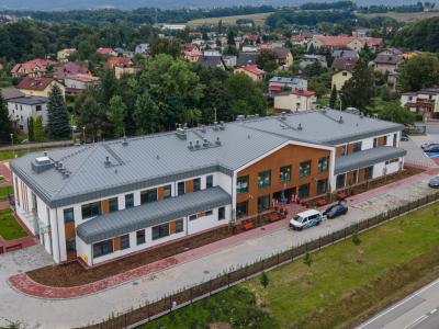 Zdjęcie przedstawiające nowoczesny budynek przedszkola przy ul. Janowickiej z parkingiem, widziany z lotu ptaka.