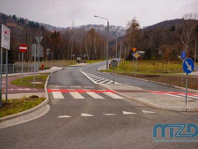 Zdjęcie przedstawiające nowo wybudowaną drogę z przejściem dla pieszych i znakami drogowymi w górskim otoczeniu.
