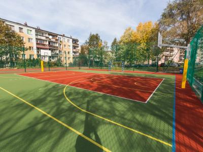 Zdjęcie przedstawiające boisko sportowe i zabudowę mieszkaniową w tle.