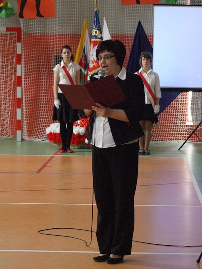 Otwarcie sali gimnastycznej - na zdjęciu przemawiająca kobieta oraz w tle poczet sztandarowy