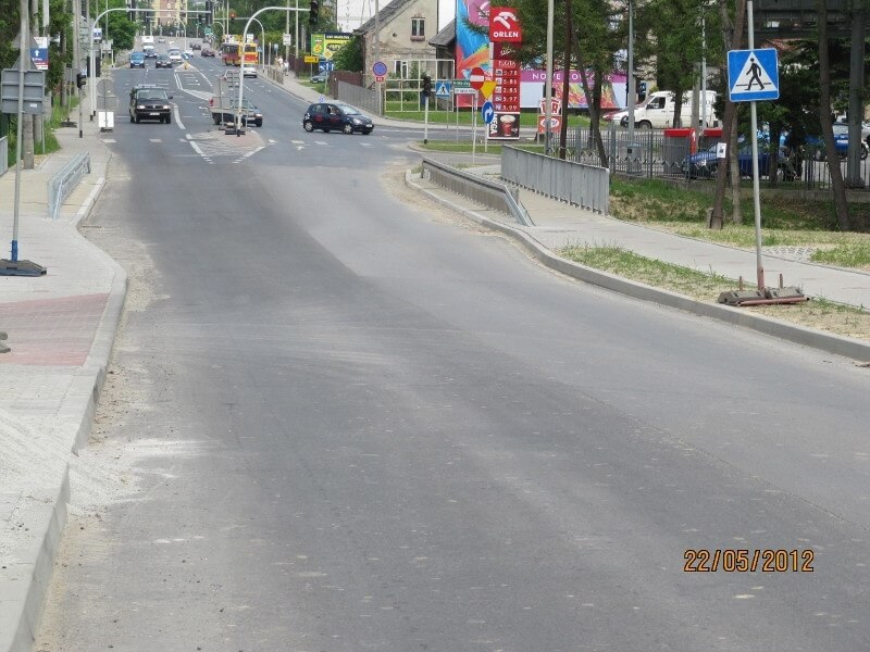 Przebudowa drogi krajowej 69 - na zdjęciu fragment drogi, znak drogowy, reklamy, budynki oraz pojazdy