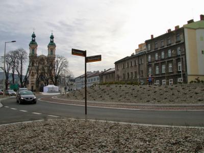 Zdjęcie przedstawiające rondo w centrum miasta z kościołem w tle i zabudową mieszkalną.