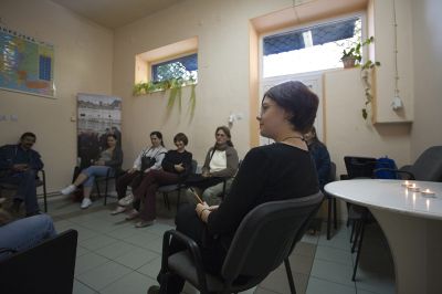 zdjęcie grupy osób siedzących w kręgu podczas spotkania w kameralnym pomieszczeniu