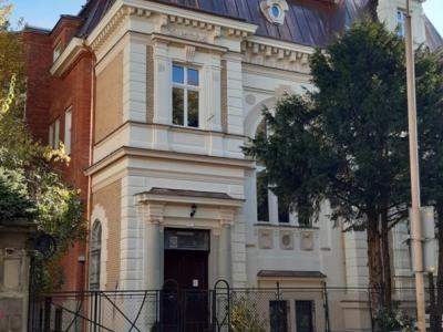 Zdjęcie przedstawiające zabytkową kamienicę z ozdobną fasadą i stromym dachem.