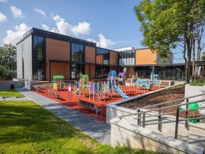 Zdjęcie przedstawiające kolorowy plac zabaw przy nowoczesnym budynku z dużymi oknami.