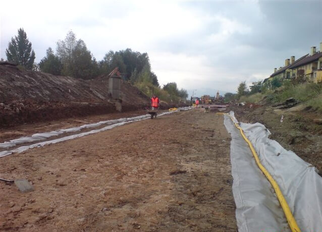 Budowa ul. Sarni Potok w Bielsku-Białej - na zdjęciu fragment budowy drogi, pracownik, budynek mieszkalny oraz zieleń