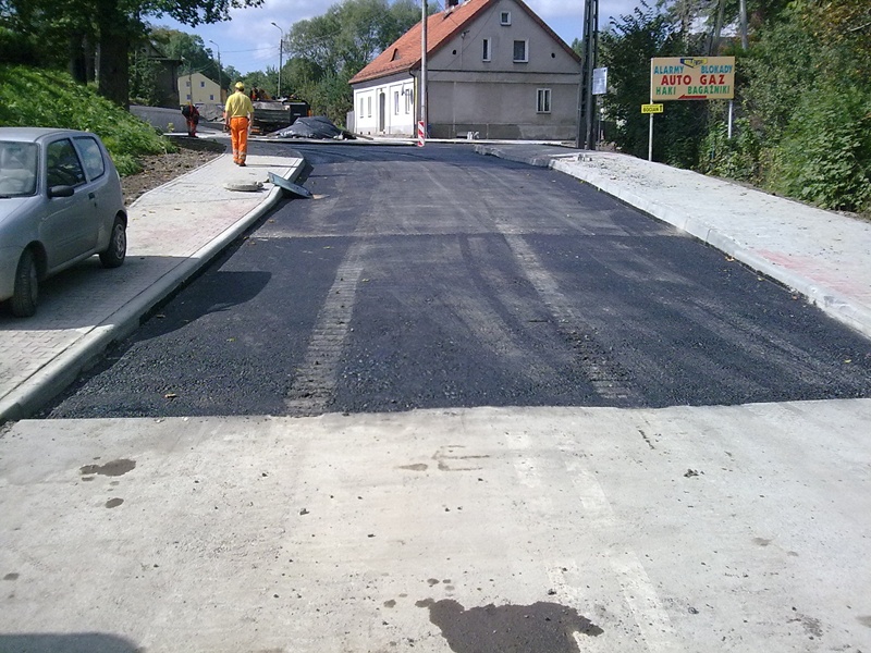 Przebudowa ul. Sobieskiego w Bielsku-Białej - na zdjęciu fragment drogi, pieszy, samochód, budynek oraz zieleń