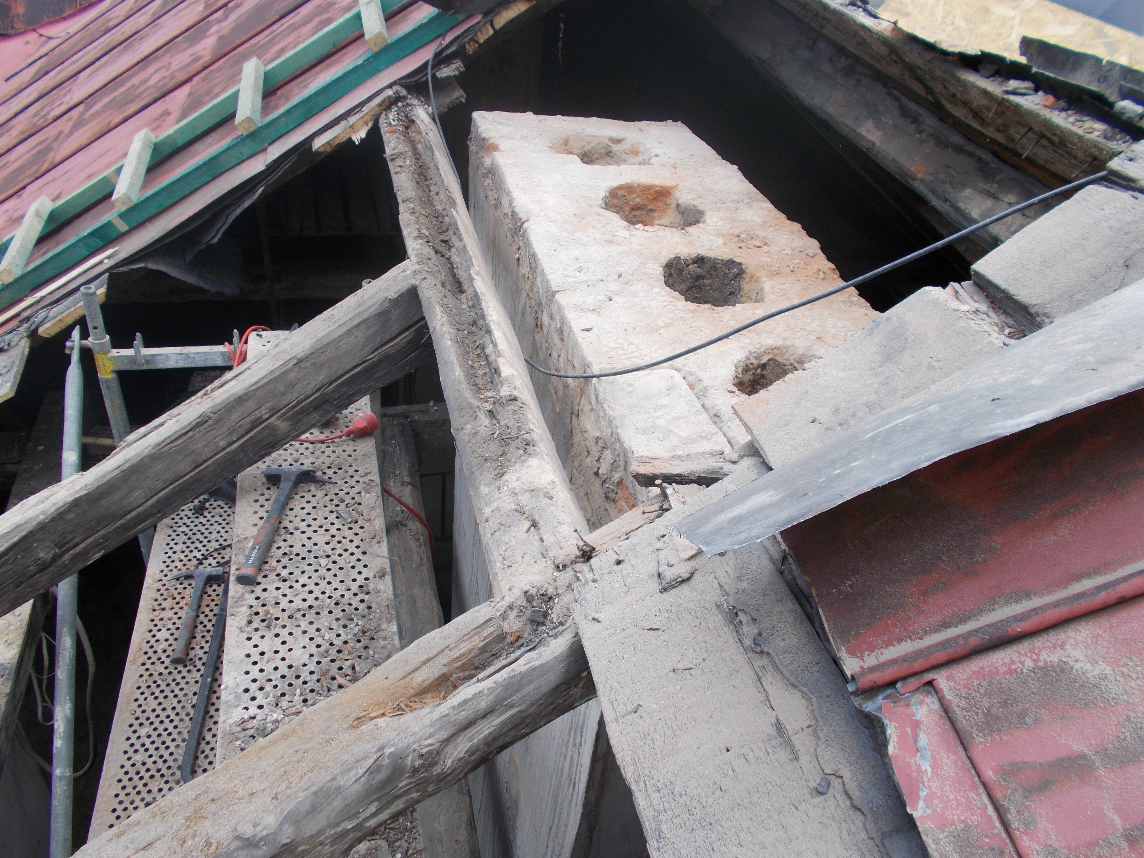 Rozebrane korony komina i widoczne zużyte pokrycie z blachy.