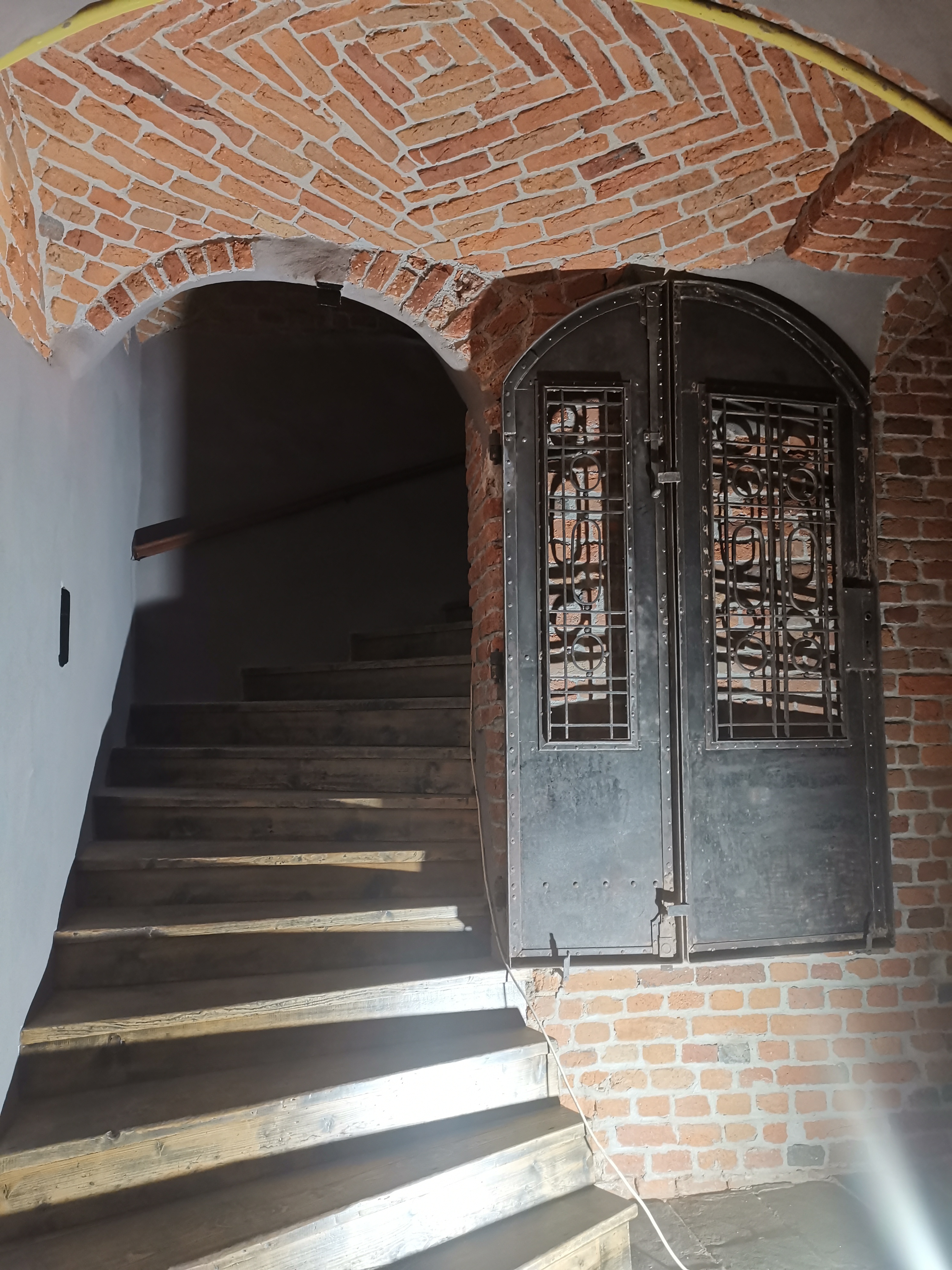 Wejście na klatkę schodową, po prawej eksponowana metalowa ślusarka.
