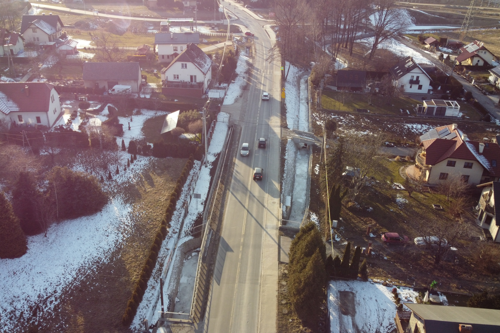 Zdjęcie przedstawiające drogę biegnącą pomiędzy nieruchomościami zabudowanymi budynkami jednorodzinnymi.