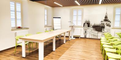 zdjęcie przedstawiające sale ze stołem, krzesłami, flipchartem oraz mównicą