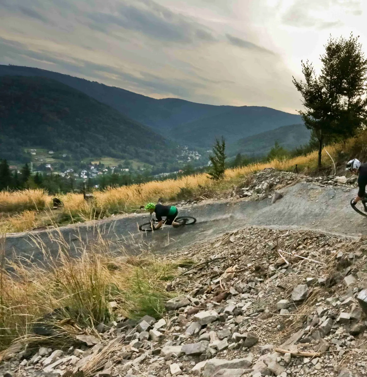 Zdjęcie przedstawiające dwóch kolarzy zjazdowych jadących po ścieżce do zjazdów enduro.