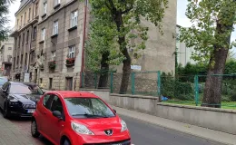 Zdjęcie budynku przy ul. Andrzeja Frycza Modrzewskiego 2 z ulicy z zaparkowanymi przed budynkiem samochodami