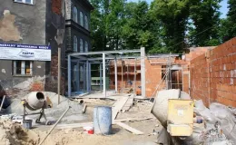 Budowa sali gimnastycznej - na zdjęciu fragment budowy, budynek oraz zieleń