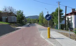 Przebudowa ul. Ks. Brzóski w Bielsku-Białej- na zdjęciu fragment drogi, znak drogowy, budynki oraz zieleń