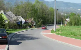 Przebudowa ul. Ks. Brzóski w Bielsku-Białej -  na zdjęciu fragment drogi, budynki, chodniki, samochody oraz zieleń