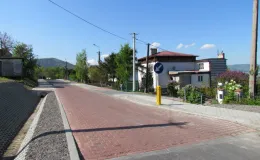 Przebudowa ul. Ks. Brzóski w Bielsku-Białej - na zdjęciu fragment drogi, znak drogowy, budynki oraz zieleń