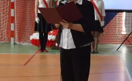 Otwarcie sali gimnastycznej - na zdjęciu przemawiająca kobieta oraz w tle poczet sztandarowy