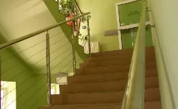 na zdjęciu schody wewnętrzne z poręczą i zielonymi ścianami prowadzące na piętro