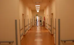 na zdjęciu jasny szpitalny korytarz z poręczami wzdłuż ścian i drzwiami do sal