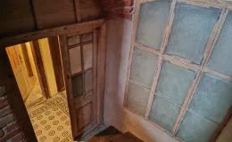 Fragment klatki schodowej z widokiem na posadzkę ceramiczną w korytarzu i stolarkę.