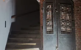 Wejście na klatkę schodową, po prawej eksponowana metalowa ślusarka.