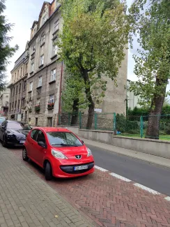 Zdjęcie budynku przy ul. Andrzeja Frycza Modrzewskiego 2 z ulicy z zaparkowanymi przed budynkiem samochodami