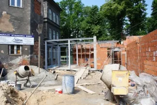 Budowa sali gimnastycznej - na zdjęciu fragment budowy, budynek oraz zieleń