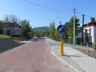 Przebudowa ul. Ks. Brzóski w Bielsku-Białej- na zdjęciu fragment drogi, znak drogowy, budynki oraz zieleń