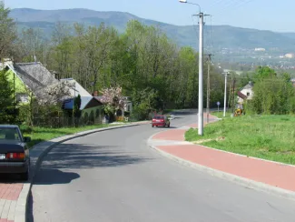 Przebudowa ul. Ks. Brzóski w Bielsku-Białej -  na zdjęciu fragment drogi, budynki, chodniki, samochody oraz zieleń