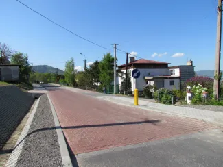 Przebudowa ul. Ks. Brzóski w Bielsku-Białej - na zdjęciu fragment drogi, znak drogowy, budynki oraz zieleń