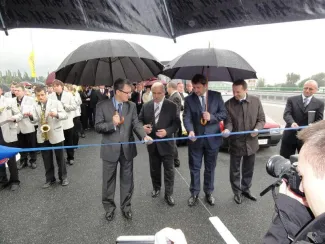 Przebudowa odcinka drogi krajowej nr 52 - na zdjęciu uroczyste przecięcie wstęgi przez delegatów w towarzystwie orkiestry i reportera