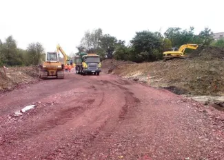 Budowa ul. Sarni Potok w Bielsku-Białej - na zdjęciu budowa drogi, maszyny budowlane oraz zieleń