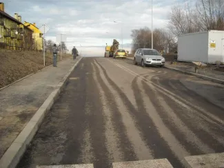 Budowa ul. Sarni Potok w Bielsku-Białej - na zdjęciu fragment drogi, blok mieszkalny oraz samochody