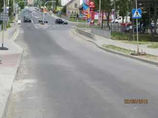 Przebudowa drogi krajowej 69 - na zdjęciu fragment drogi, znak drogowy, reklamy, budynki oraz pojazdy