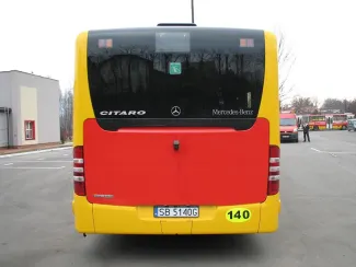 Zakupione autobusy niskopodłogowe marki Mercedes - na zdjęciu tył autobusu, pojazd oraz budynek