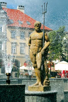 zdjęcie Starówki w Bielsku-Białej przedstawiające Posejdona przy fontannie na tle kamienicy i ogródków gastronomicznych
