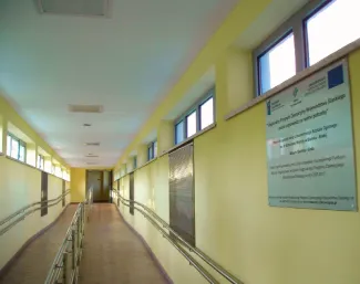 na zdjęciu jasny korytarz z pochylnią i tablicą informacyjną o dofinansowaniu z UE
