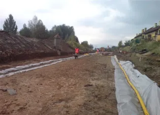 Budowa ul. Sarni Potok w Bielsku-Białej - na zdjęciu fragment budowy drogi, pracownik, budynek mieszkalny oraz zieleń