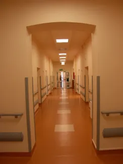 na zdjęciu jasny szpitalny korytarz z poręczami wzdłuż ścian i drzwiami do sal