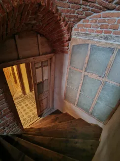 Fragment klatki schodowej z widokiem na posadzkę ceramiczną w korytarzu i stolarkę.