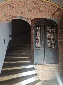 Wejście na klatkę schodową, po prawej eksponowana metalowa ślusarka.
