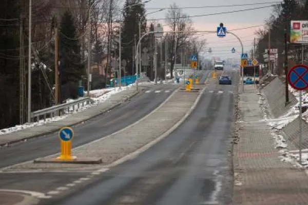 Zdjęcie przedstawiające ulicę z wyspą rozdzielającą pasy ruchu i znakami przejścia dla pieszych zimą.