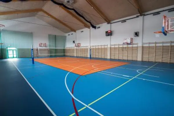 Zdjęcie przedstawiające salę gimnastyczną z boiskiem do siatkówki i koszykówki.