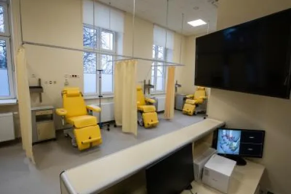 Zdjęcie przedstawiające gabinet medyczny z żółtymi fotelami zabiegowymi oddzielonymi zasłonami.