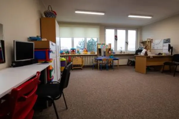 Zdjęcie przedstawiające pokój do zajęć terapeutycznych z biurkami, komputerami i zabawkami dla dzieci.